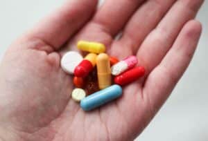 Eine Hand mit vielen verschiedenen Medikamenten: Kapseln, Pillen & Tabletten, die Wechselwirkungen haben können