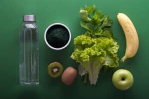 Wasserflasche, Banane, Apfel, Salat und Kiwi. Gesunde Lebensmittel, die oft bei Ernährungsberatungen empfohlen werden
