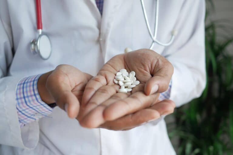 Hand mit Tabletten, die wie Pantoprazol aussehen