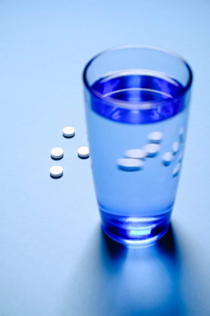 Vergessene Cholesterin Tabletten neben einem Wasserglas